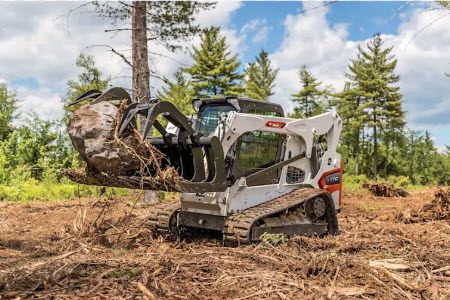 Track loader clearing a stump from open ground
